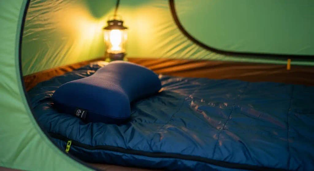Compact travel-size memory foam camping pillow on a sleeping bag inside a tent, side view